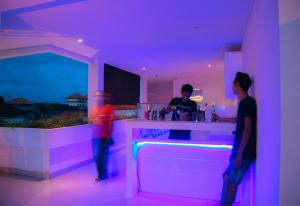 dos personas de pie en un bar con luces moradas en Deva Bali Apartement, en Kerobokan