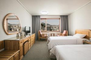 Habitación de hotel con 2 camas y espejo en Busan Tourist Hotel en Busan