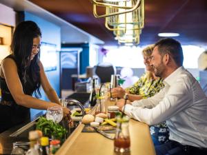 a group of people sitting at a bar preparing food at Mercure Toulouse Centre Saint-Georges in Toulouse