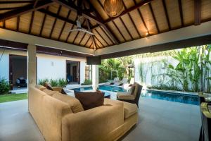an outdoor living room with a couch and a swimming pool at Arama Riverside in Legian