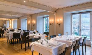 a restaurant with white tables and chairs and windows at Schloss Münchenwiler in Murten