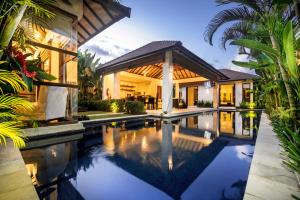a house with a swimming pool in front of a house at Arama Riverside 5 Bedrooms by Villas Direct Bali in Legian