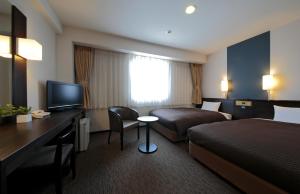 高知市にある西鉄イン高知はりまや橋のベッド、デスク、ベッド、テレビが備わるホテルルームです。