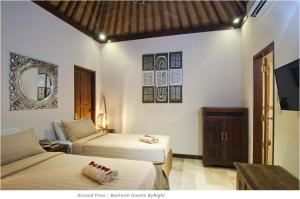 1 Schlafzimmer mit 2 Betten, einem Spiegel und einem TV in der Unterkunft 2BR Villa Senin - Minggu Villas Seminyak in Seminyak