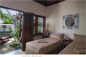 1 Schlafzimmer mit 2 Betten und einem Wandspiegel in der Unterkunft 2BR Villa Senin - Minggu Villas Seminyak in Seminyak