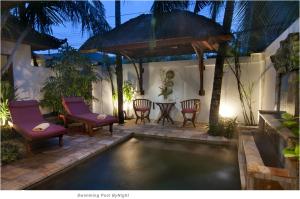 einen Pool im Hinterhof mit Stühlen und einem Tisch in der Unterkunft 2BR Villa Senin - Minggu Villas Seminyak in Seminyak