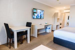 een hotelkamer met een bureau en een bed bij Balan Village Motel in Nowra