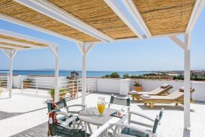 een patio met een tafel en stoelen en de oceaan bij Aptera Beach in Amoudara Herakliou