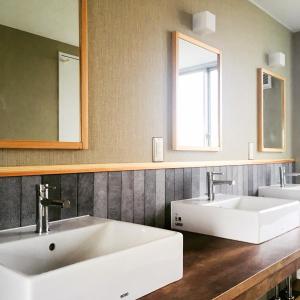 a bathroom with two sinks and two mirrors at En Hostel & Bar in Kochi