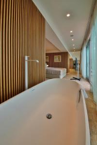 a large white bath tub in a room with a bed at Flamingo Grand Hotel & Spa in Albena