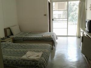 a hotel room with two beds and a television at M In Korat Service Apartment in Nakhon Ratchasima