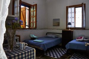 a bedroom with two beds and a table and windows at Moorea Country Houses in Petalidhion