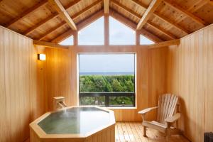 ein Bad mit einer Badewanne, einem Stuhl und einem Fenster in der Unterkunft Awaji International Hotel The Sunplaza in Sumoto