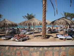 a beach with people laying on lounge chairs and umbrellas at Reemyvera in Hurghada