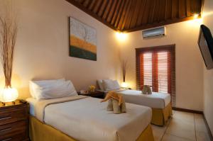 スミニャックにある4BR Villa Selasa - Minggu Villas Seminyakのベッド2台とテレビがあるホテルの部屋