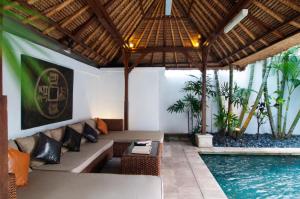 スミニャックにある4BR Villa Selasa - Minggu Villas Seminyakのリビングルーム(ソファ付)、スイミングプールが備わります。