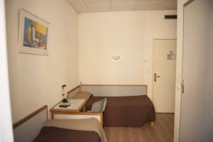 um pequeno quarto de hotel com 2 camas e uma secretária em Hotel du Palais em Ajaccio