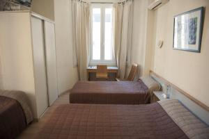 a room with two beds and a table and a window at Hotel du Palais in Ajaccio