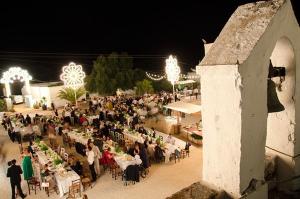 una gran multitud de personas sentadas en las mesas por la noche en Masseria Mozzone, en Fasano