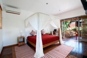 a bedroom with a red bed with a canopy at 3BR Villa Hari - Minggu Villas Seminyak in Seminyak +16 photos
