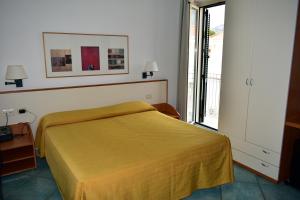 a bedroom with a yellow bed and a window at Hotel Amyclae in Sperlonga