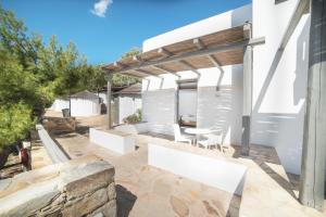 a patio with a table and chairs under a pergola at FarOut - BeachResort & Camping in Mylopotas