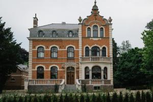 een groot bakstenen gebouw met een toren bij Villa Copis in Borgloon