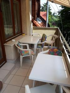 un balcón con mesas y sillas en un porche en Magdi apartman en Keszthely