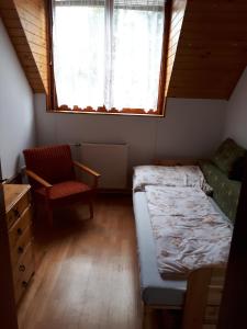 a bedroom with a bed and a chair and a window at Magdi apartman in Keszthely