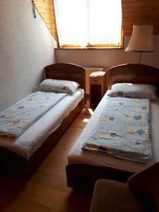 two beds in a small room with a window at Magdi apartman in Keszthely