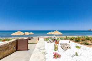 een strand met rieten parasols en de oceaan bij Iris Luxury Beach Front Residence with Pool & BBQ, By ThinkVilla in Rethimnon +24 foto's