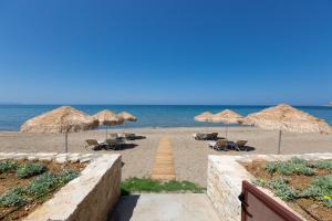een zandstrand met parasols en stoelen en de oceaan bij Iris Luxury Beach Front Residence with Pool & BBQ, By ThinkVilla in Rethimnon