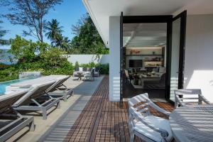 eine Außenterrasse mit Tischen und Stühlen sowie ein Wohnzimmer in der Unterkunft Rosewood Phuket - SHA Plus in Patong Beach