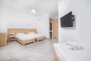 a room with two beds and a flat screen tv at FarOut - BeachResort & Camping in Mylopotas