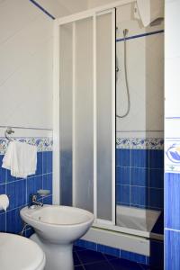 a blue and white bathroom with a toilet and a shower at Hotel Amyclae in Sperlonga