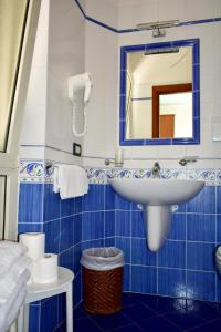 a blue tiled bathroom with a sink and a mirror at Hotel Amyclae in Sperlonga