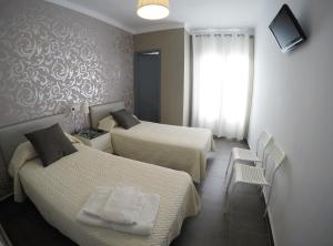 um quarto de hotel com duas camas e uma janela em Hostal Mediterráneo em Tossa de Mar