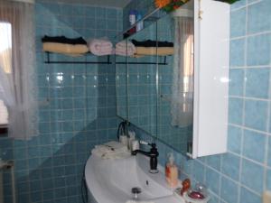 a blue tiled bathroom with a sink and a mirror at Ferienwohnung in Bohndorf +8 photos