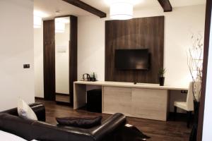a living room with a couch and a tv on a wall at Hotel U Kašny in Rajhrad