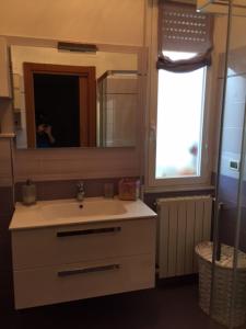 een badkamer met een witte wastafel en een spiegel bij La cà du cavallu in Noli