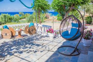 a patio with a swing and a table and chairs at Ammos Apartments in Alikanas