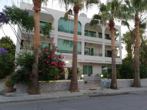 a white building with palm trees in front of it at Marianna Hotel Apartments in Limassol