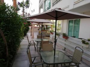 a patio with tables and chairs and an umbrella at Marianna Hotel Apartments in Limassol