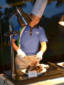 a chef preparing food on a table with a plate of food at Meru Suites at Meru Valley Resort in Ipoh