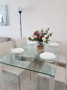 una mesa de cristal con sillas blancas y un jarrón de flores en Marianna Hotel Apartments, en Limassol