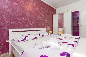 a bedroom with a white bed with purple walls at Apartments Maky & Dino in Vodice