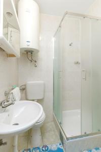 a white bathroom with a shower and a sink at Apartments Maky & Dino in Vodice +7 photos
