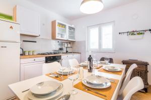 una cucina con tavolo e sedie e una cucina con armadietti bianchi di Apartment "On the beach" a Trogir