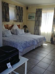 a bedroom with a bed and a suitcase on a table at A Wave from it all in Port Shepstone