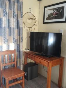 a television sitting on a wooden table with a chair at A Wave from it all in Port Shepstone